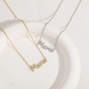 Nahaufnahme der goldenen und silbernen Mama-Buchstabenanhänger mit Zirkon auf Keramik