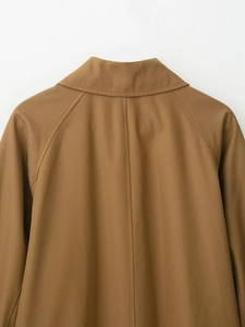 Detail of the brown trench coat featuring back neckline stitching and twill fabric texture