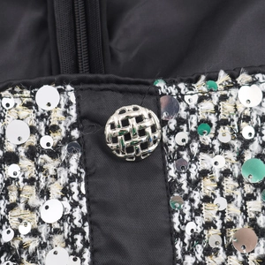 Close-up of black and white tweed sleeveless dress with silver sequins and metal button