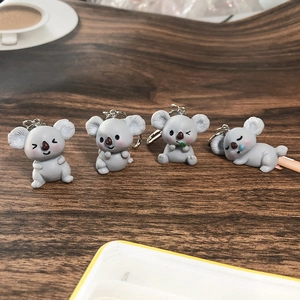 Set of four cute grey koala resin keychains with different poses on wooden surface