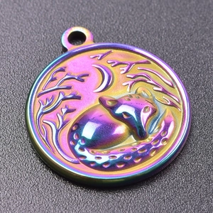 Macro view of rainbow stainless steel round charm with a fox sleeping under a moon and tree