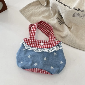 Dettaglio della borsa in denim blu a stelle con pizzo a quadretti rossi e bottone