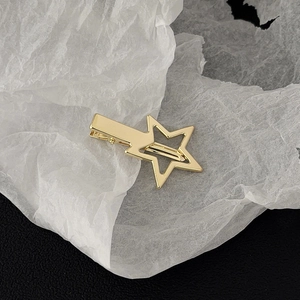 Close-up of a polished gold star-shaped duckbill hair clip on a textured background