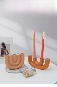 Detail van mat keramische kandelaars in warm oranje en morandi bruin op kunstmagazine