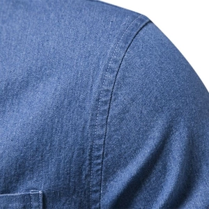 Detailed view of blue denim shirt shoulder and sleeve stitching on white background