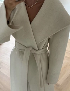 Detailed view of camel wool coat featuring oversized lapels and matching tie-waist belt