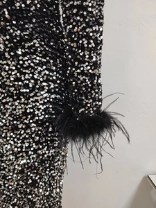 Détail de paillettes argentées et bordure en plumes d'autruche sur une manche