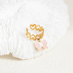 Gold stainless steel heart ring with a pink bow pendant on white coral decor