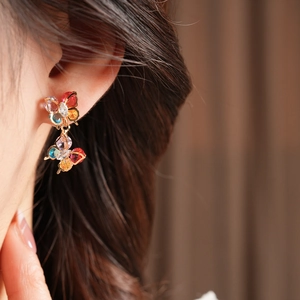 Macro view of colorful zircon butterfly earrings worn by a model in close-up detail