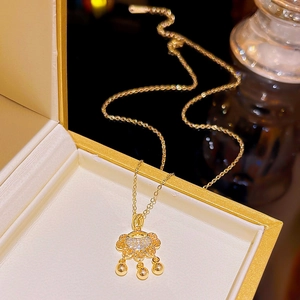 Detail of 18K gold-plated Ruyi lock necklace with small bells in a jewelry box