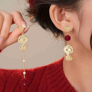 Detail of red pompom and snake charm asymmetric earrings with pearls on model