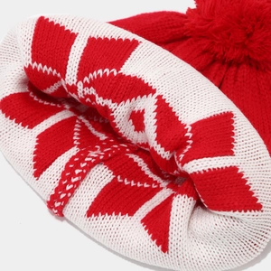 Detailed view of red and white knit beanie featuring snowflake patterns and a soft pom-pom