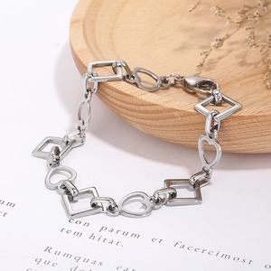 Detailed shot of silver heart and square linked stainless steel bracelet on wooden tray