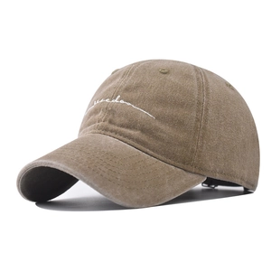 Detailed view of white cursive 'freedom' embroidery on washed cotton khaki baseball cap
