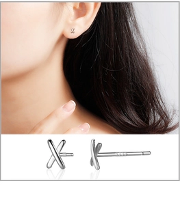 Detail of S999 sterling silver X-shaped stud earrings showing hallmark and model wear