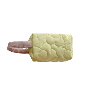 Quilted floral cosmetic bag in pale yellow with a pink handle for daily use