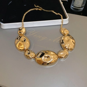 Macro detail of golden necklace showing hammered texture finish and lobster clasp