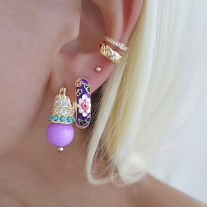 Détail de boucles d'oreilles fleur émail violet et bagues d'oreille dorées