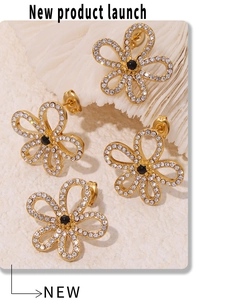 Detailed shot of golden flower earrings with clear rhinestones and black center gems