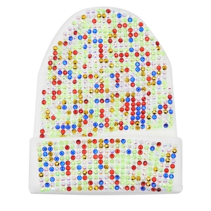 Dettaglio di strass colorati disposti in file verticali sul berretto in maglia bianca