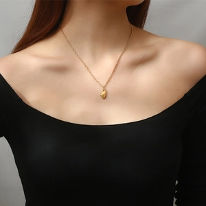 Golden irregular geometric wishing stone pendant necklace worn on a woman's collarbone
