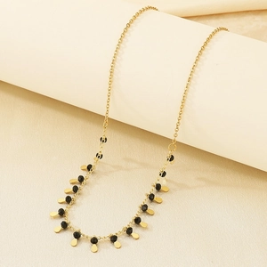 Detailed macro view of gold tassel necklace with black beads and waterdrop pendants