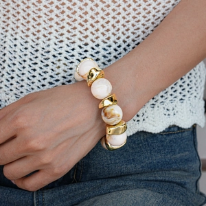Detail of vintage acrylic marble beads and golden metal spacers on a model wrist