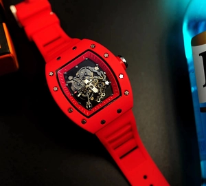 Macro detail of red tonneau-shaped skeleton watch with visible screws and rubber strap