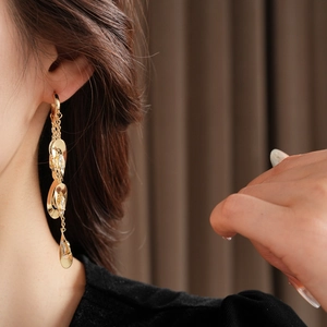 Gros plan de boucles d'oreilles pampilles dorées avec gouttes de zircon sur un mannequin