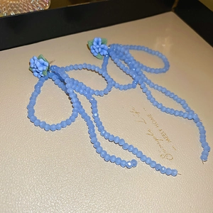 Vue détaillée de longues boucles d'oreilles pendantes bleues avec fleurs à la main