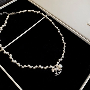 Detail of silver rocking horse pendant with zircon pavé and large pearl on a bead necklace