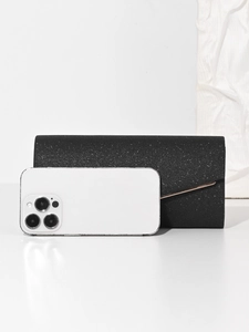 Detail view of black glitter evening clutch bag shown next to a smartphone for size reference