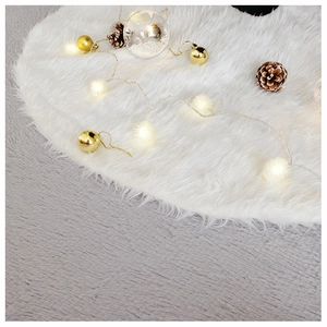 Detail of soft white plush Christmas tree skirt with festive ornaments and warm lights
