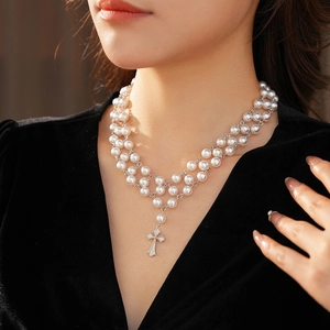 Detail of layered pearl necklace with a sparkling crystal cross pendant for women