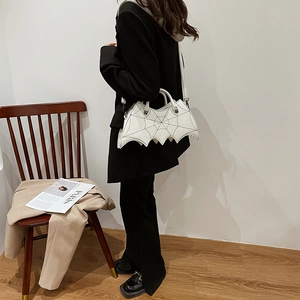 Detail view of a white bat-shaped PU bag with spiderweb stitching and skull metal accents