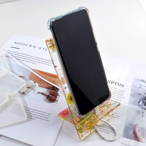 Detail of DIY epoxy resin phone stand featuring dried pink flowers and gold foil flakes