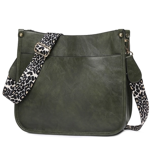 Detail of dark green leather crossbody bag featuring a leopard print wide strap and gold hardware