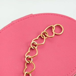 Detail of pink pebbled leather with a gold hollow heart-shaped chain and OT buckle