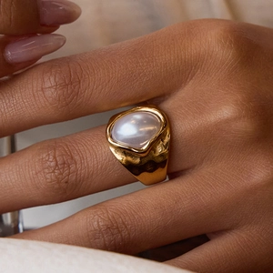 Detailansicht eines breiten goldenen Hammerschlag-Rings mit großer weißer Perle
