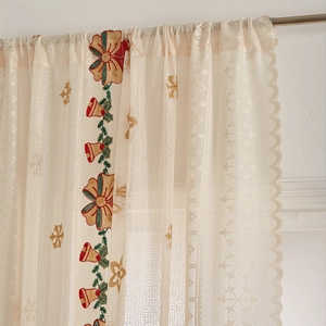 Close-up of Christmas lace curtain featuring red bell embroidery and scalloped edges