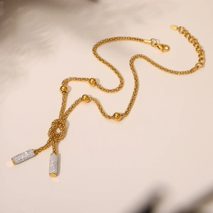 Detail of PVD gold plated beaded chain necklace featuring a crystal encrusted knot pendant