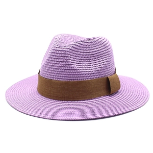 Detail of purple woven fedora straw hat featuring a wide brown ribbon and fine texture
