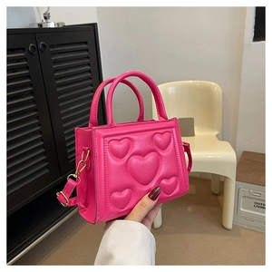 Détail du petit sac rose fuchsia avec cœurs en relief et bandoulière chaîne dorée