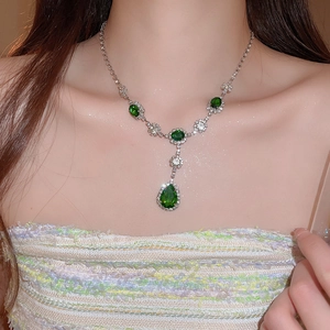 Primo piano della collana d'argento con pendente a goccia verde smeraldo e piccoli cristalli