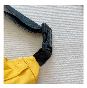 Close-up of durable black nylon strap and plastic buckle on bright yellow canvas bag
