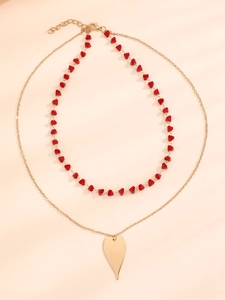 Détail du collier à deux rangs avec perles rouges facettées et pendentif cœur doré