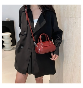 Glossy red mini crossbody bag with curved zipper detail worn by a model on shoulder
