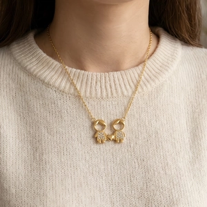 Collier doré avec pendentif couple garçon et fille et cœur sur pull blanc