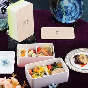 Detail view of oval wood-grain lunch box with cutlery set on an artistic tabletop
