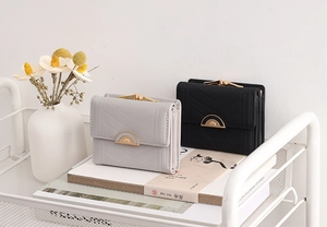 Close-up of grey and black short wallets with V-shaped quilting and gold buckles